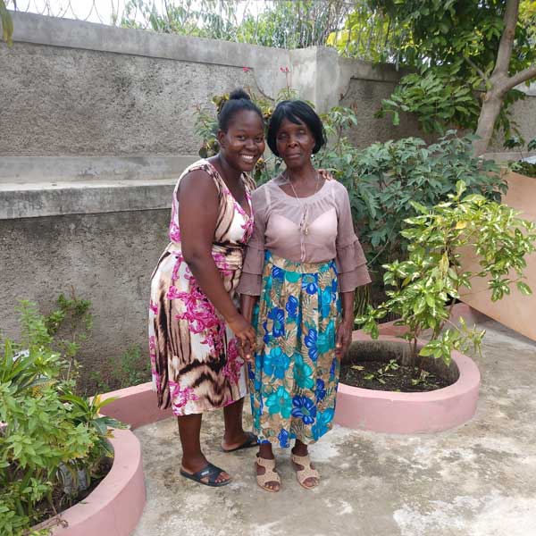 Two women standing next to each other in a garden.