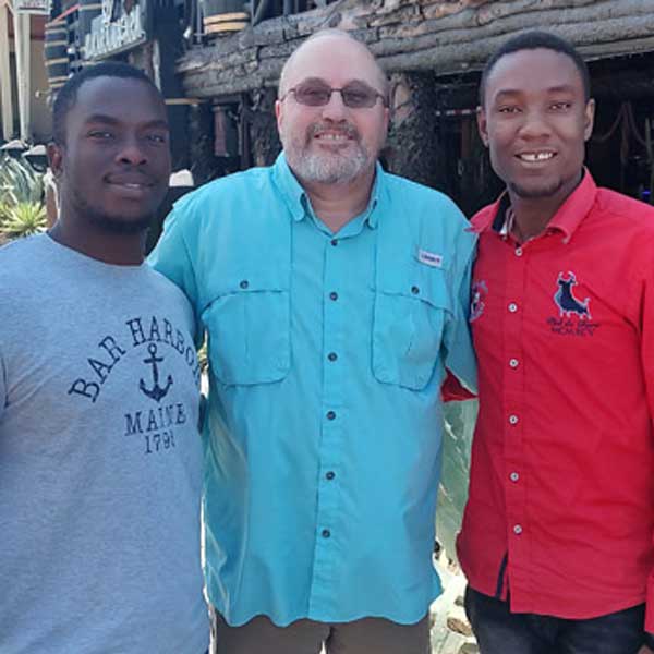 Three people representing Haiti's impoverished communities posing for a picture in front of a building.